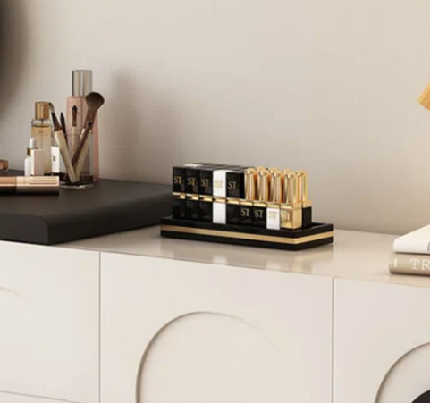 Makeup products including lipsticks and brushes on a counter with a neutral background