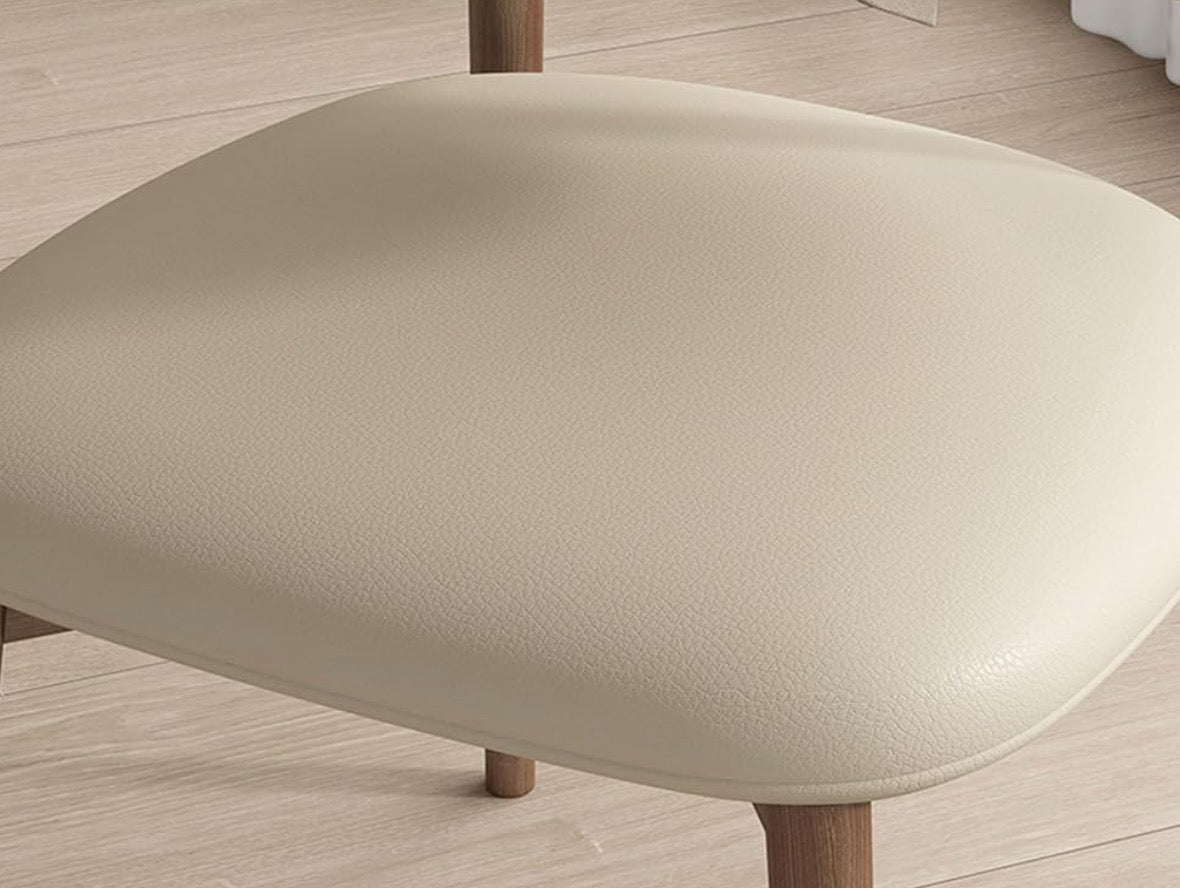 Close-up of a beige ottoman with wooden legs on a light wood floor.