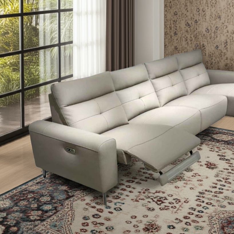 Gray sectional sofa in a living room with large windows and a patterned rug.