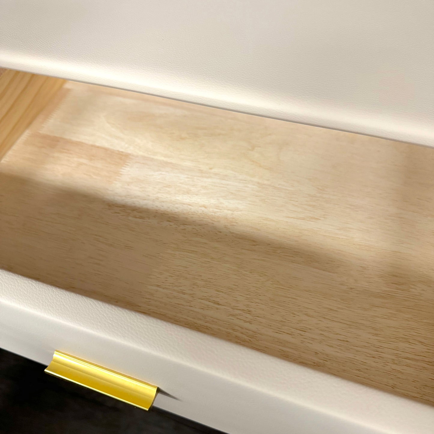 Close-up of a wooden nightstabd drawer with a gold handle