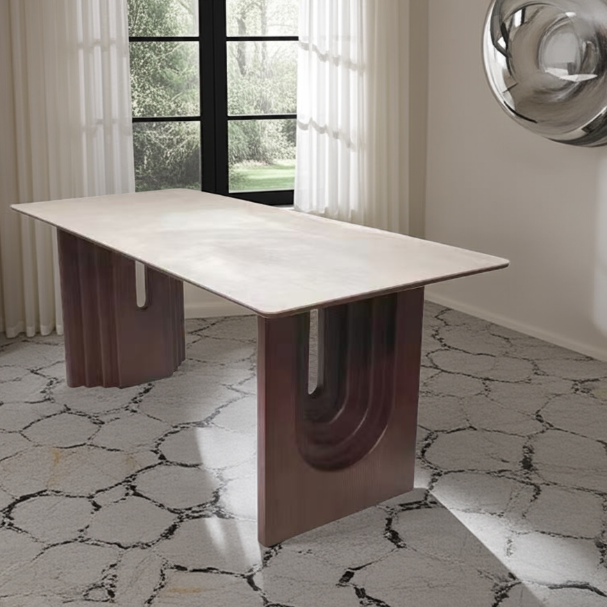 Modern dining table with unique base design in a room with large windows.
