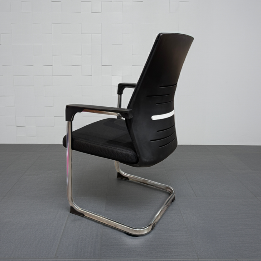Black office chair with chrome legs on a gray floor and white tiled wall background