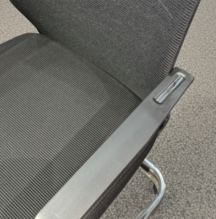 Gray office chair with armrest on a carpeted floor