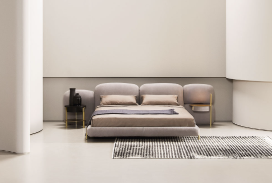 Modern bedroom with a bed, chair, and wall-mounted lamp in a minimalistic setting.
