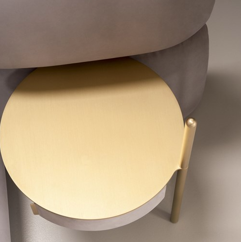 Round beige stool with a gold leg on a neutral background