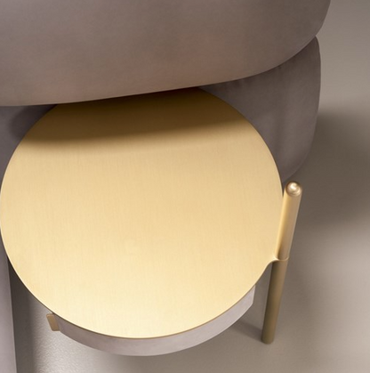 Round beige stool with a gold leg on a neutral background