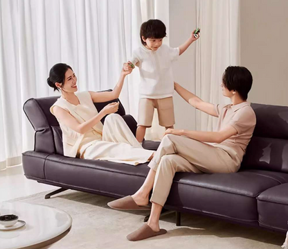 Family of three sitting on a dark purple sofa in a bright living room genesis furniture