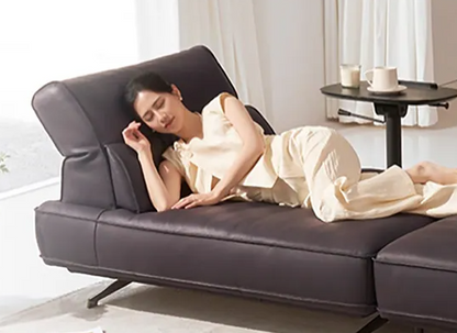 Woman lying on a dark gray sofa in a bright room with a small table in the background genesis furniture