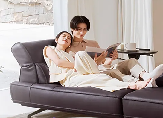Couples sitting on a brown leather couch, one reading a book genesis furniture