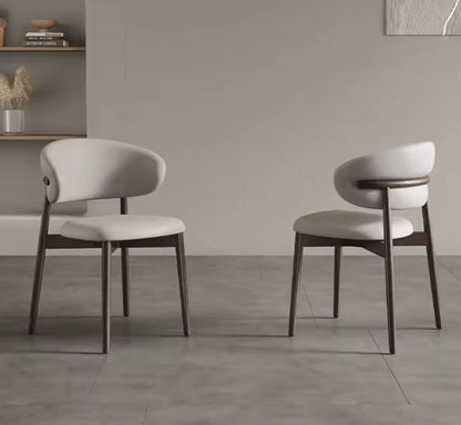 Two modern chairs with white seats and dark wooden legs in a minimalistic room.
