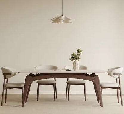 Dining room with a wooden table and chairs against a plain wall.