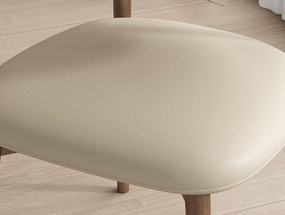 Close-up of a beige ottoman with wooden legs on a light wood floor.