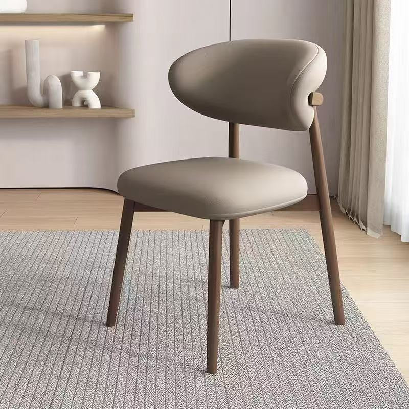 Beige chair with wooden legs in a room with a rug and shelves.