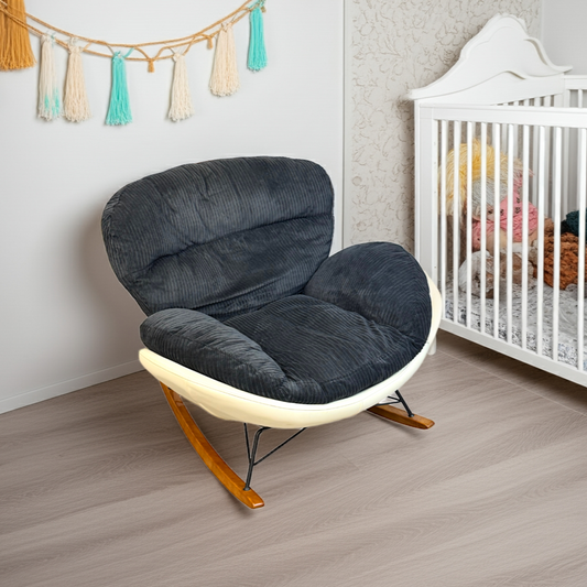 Gray cushioned chair in a room with a crib and decorative tassels on the wall.