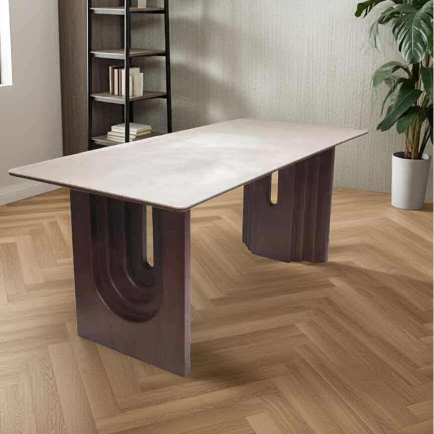 Modern dining table with unique U-shaped legs in a room with a bookshelf and plant.