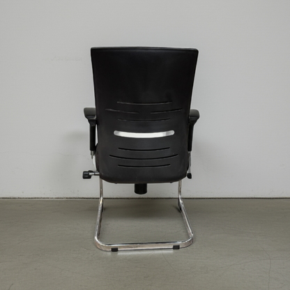 Black office chair with chrome legs on a gray floor and white wall